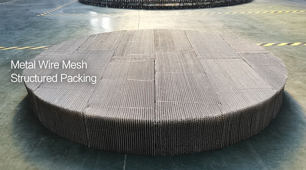 Metal wire mesh structured packing discs stacked inside a distillation column with liquid distributor above